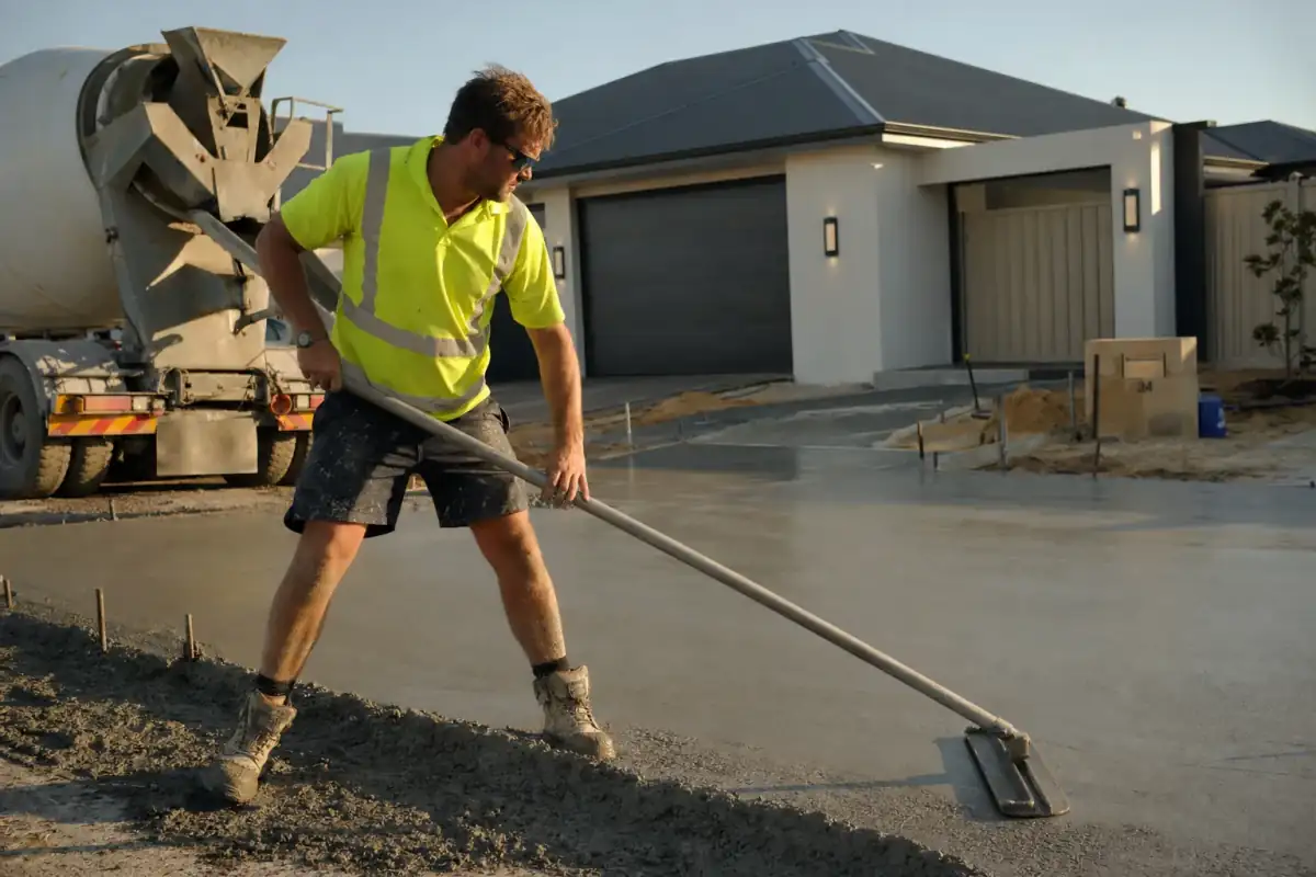Concrete Contractors Perth tradie bull-floating a freshly poured residential driveway in golden afternoon light