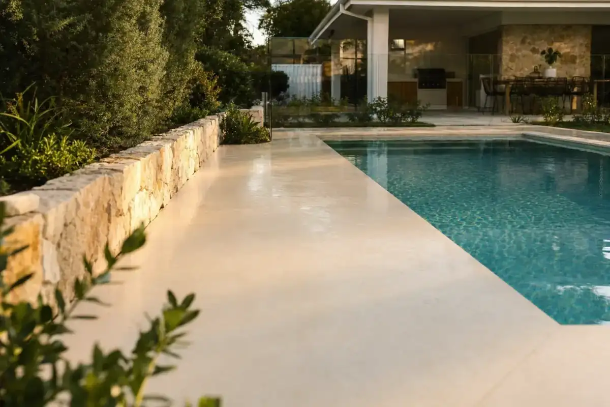 Freshly finished liquid limestone pool surround in Perth, smooth pale surface reflecting afternoon light beside a residential swimming pool